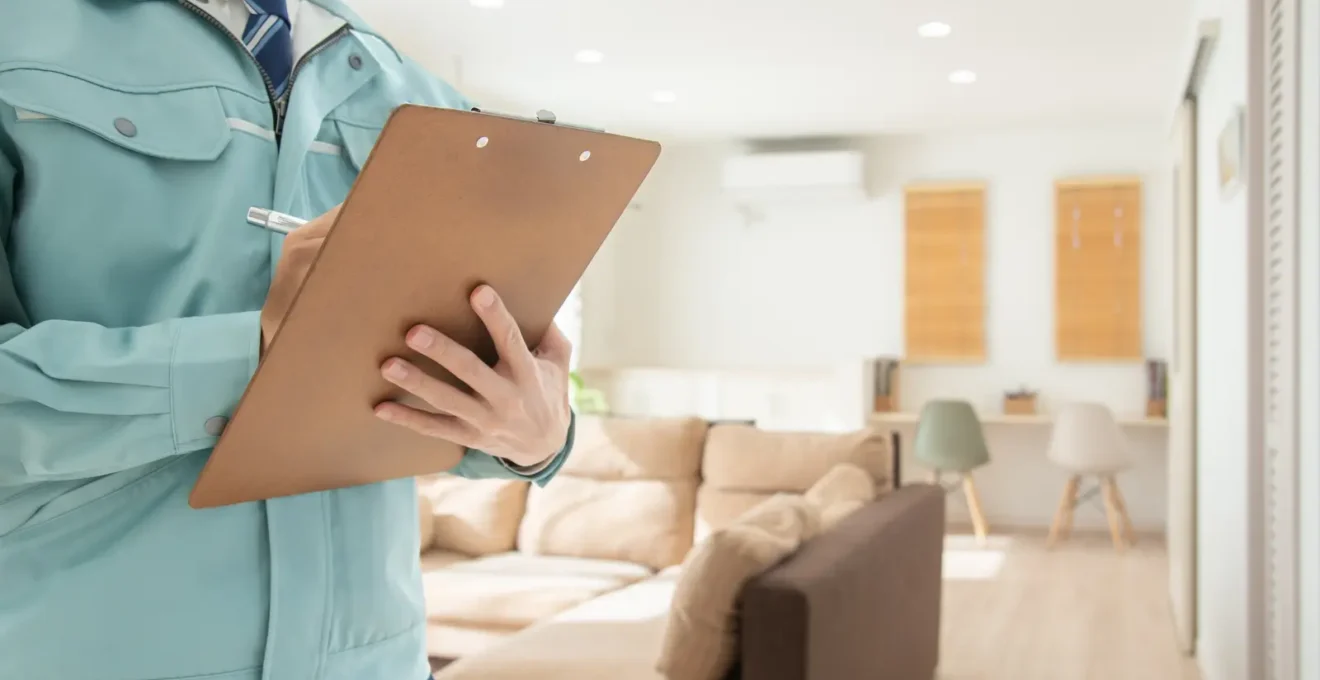 Un agent immobilier mesure une pièce avec un télémètre laser pendant une estimation chez un propriétaire.